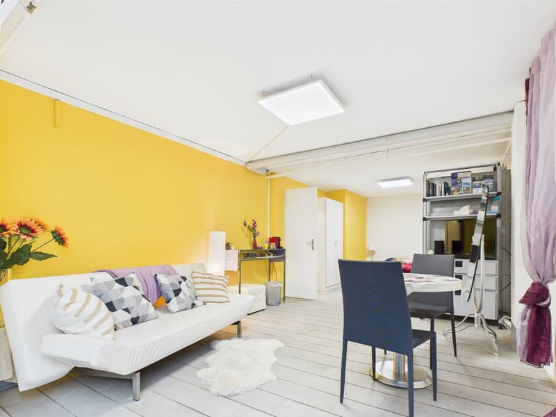 White living couch, colorful pillows, dining table, yellow walls, shelving unit, floor lamp