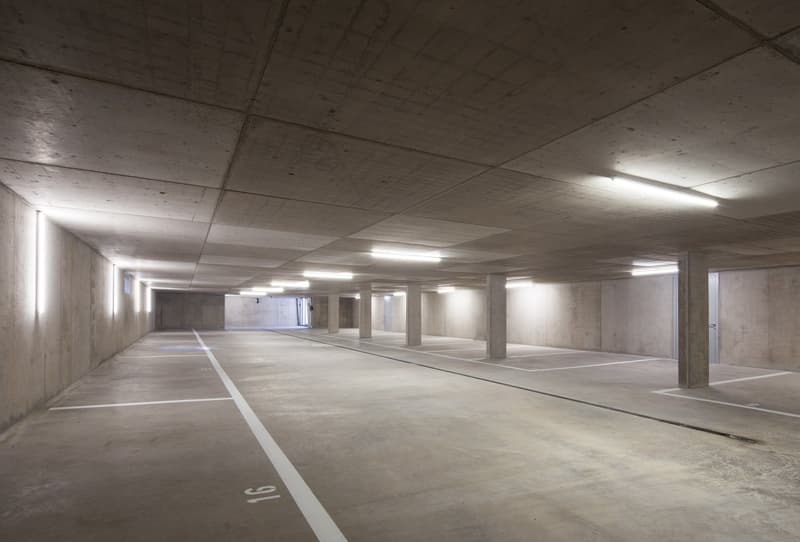 an empty parking lot with concrete walls, pillars, and lighting