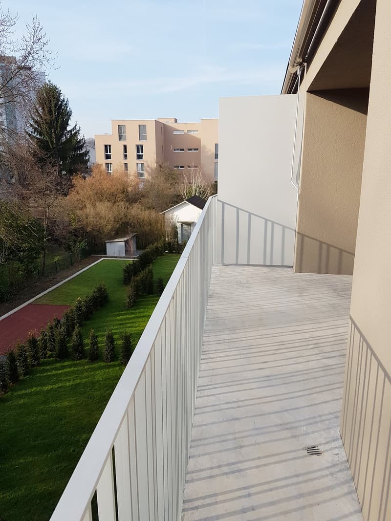 Concrete floor, white railings, large grassy area in the background