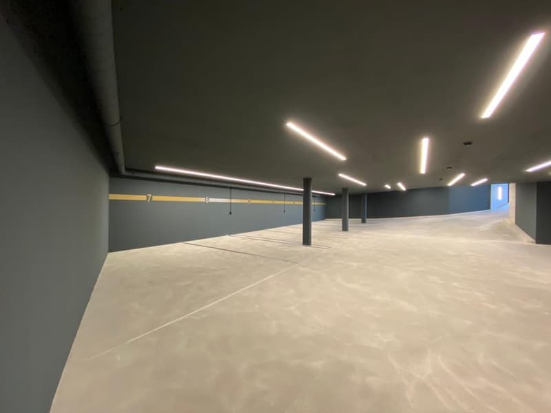 empty parking room, gray walls, white floor, fluorescent lights
