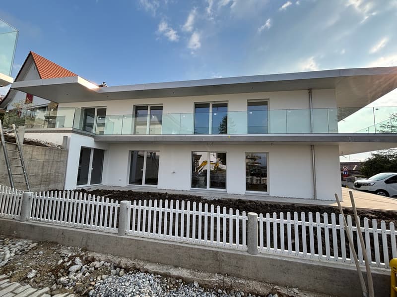 Modern 2 story house, white exterior, glass railings on balcony, large windows, concrete foundation
