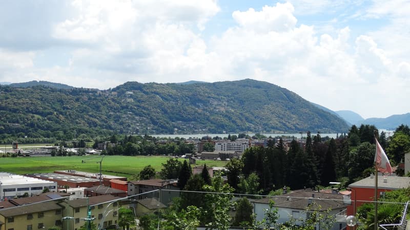 Aerial view of a town with buildings, mountains, and a lake in the background
