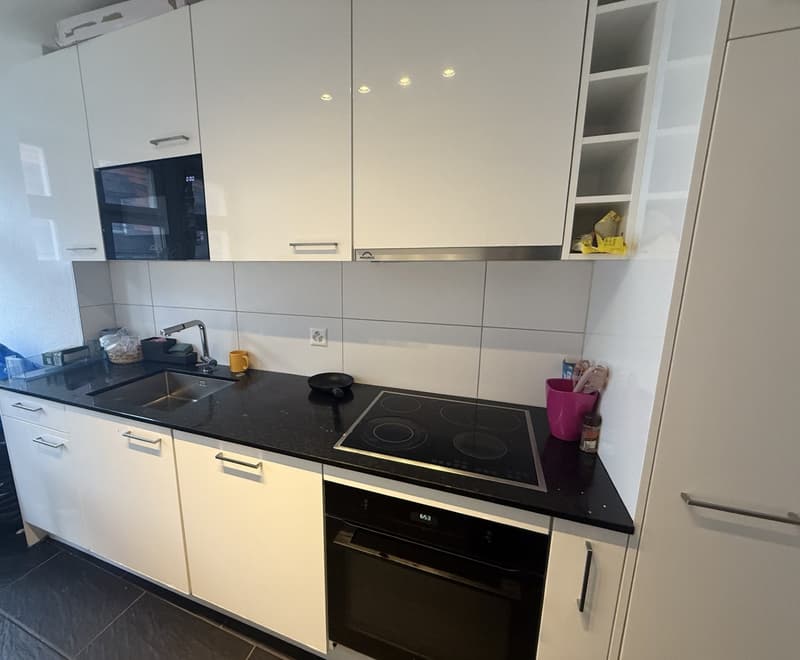 modern fitted kitchen with white units and black worktops, oven and hob, sink, microwave, and a dishwasher
