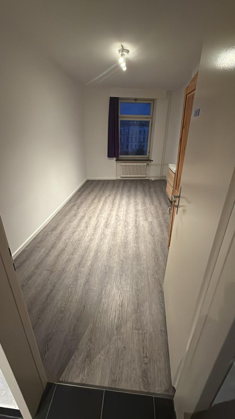 empty room, wooden floors, white walls, a window with white radiator, open door