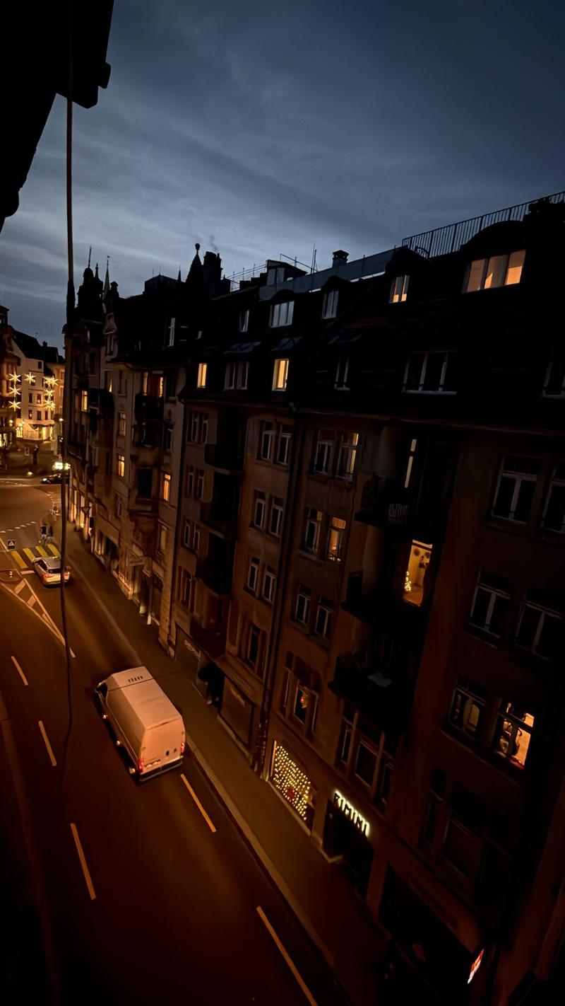 An aerial view of a street during the night with cars passing by, streetlights, and buildings