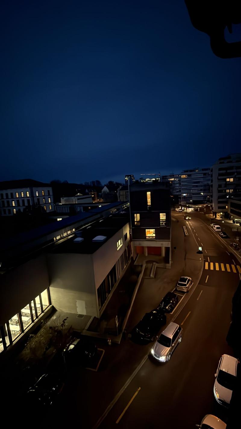 Multi-storey buildings, road, cars parked on the side, street lights, city view at night
