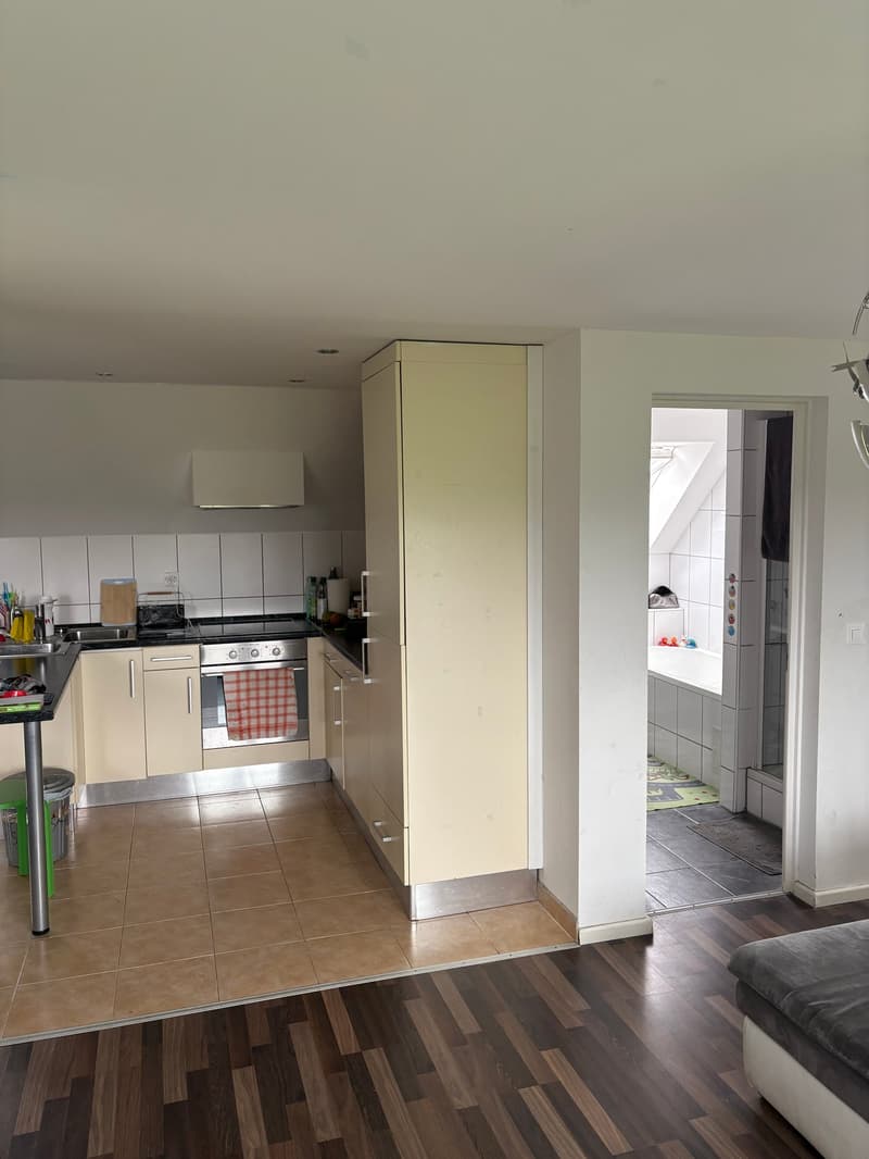 modern kitchen with tiled floor, white cabinets, stainless steel oven and countertop, sink, and trash can