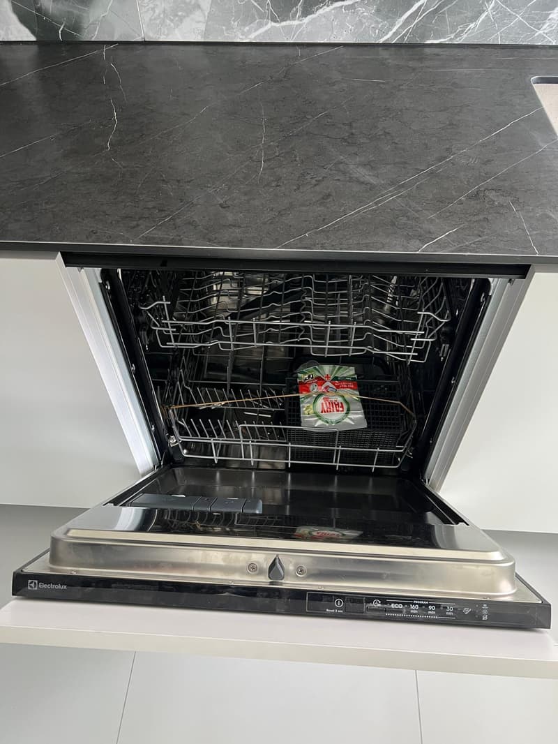 Open dishwasher with a bag of dishwasher tablets inside