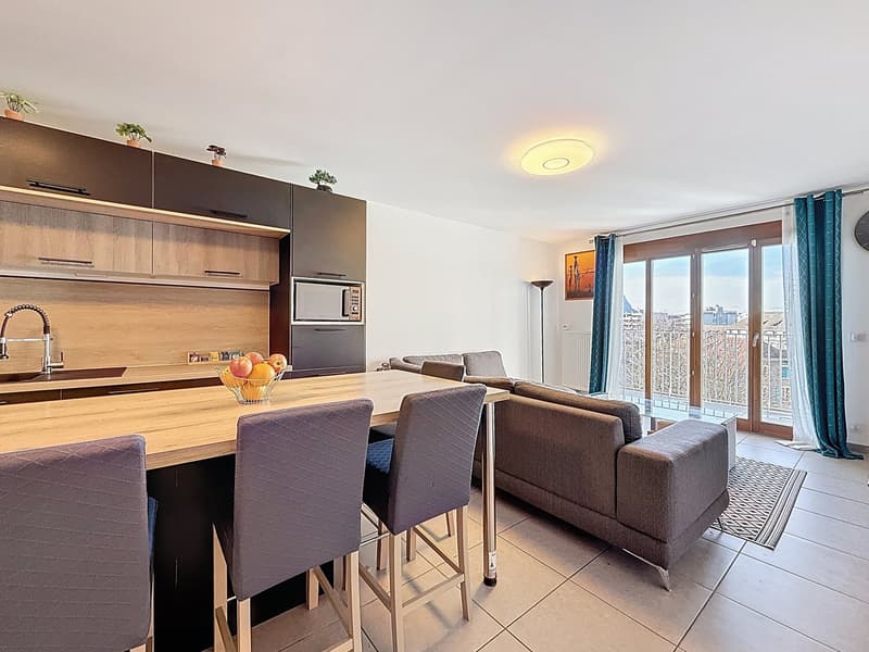 Open kitchen with dining area, living room with couch, balcony with view, modern decor