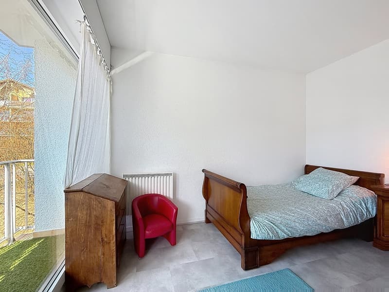 bedroom with bed, chair, wooden cabinet, radiator, carpet, balcony with railing, view of trees