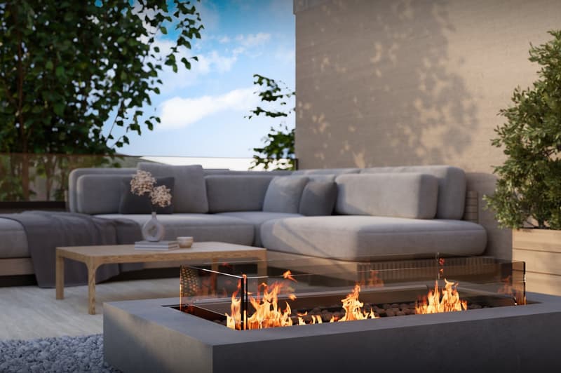 Firepit with glass cover, surrounded by rocks, couch with pillows, wooden table, plant