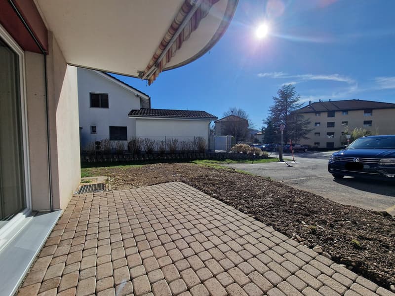 brick paved walkway, car parked in parking lot, white building, trees, clear sky