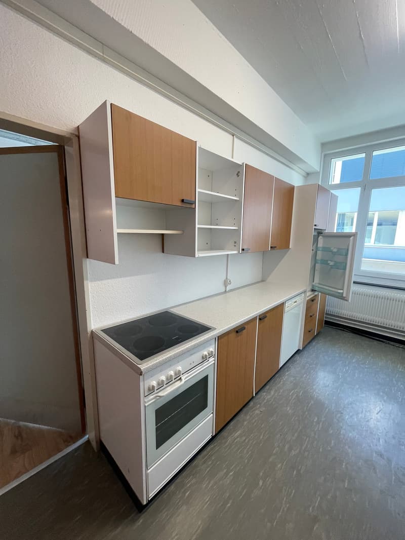 Empty kitchen with wooden cabinets, white appliances, a refrigerator, a gas stove, and a dishwasher