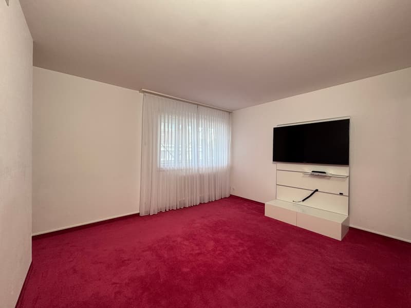Empty room with white walls, red carpet, white curtains, flatscreen TV, media console