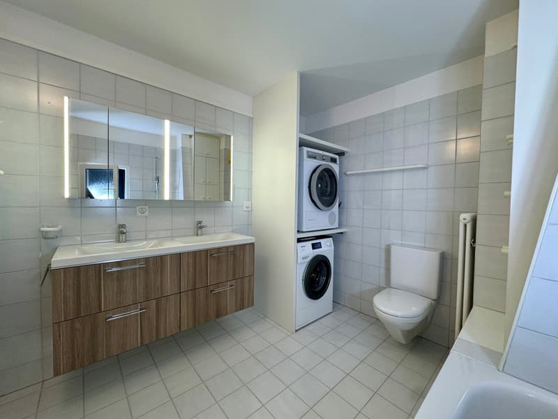 modern bathroom, white tile, wooden cabinet, double sink, washing machine, toilet, bathtub