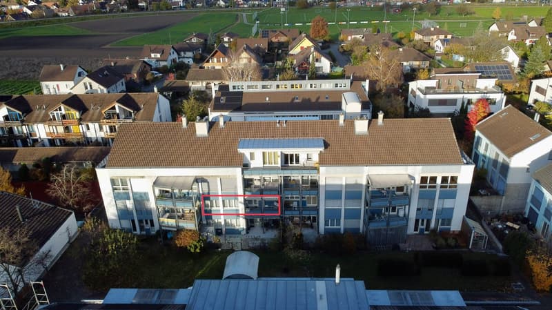 Residential building with several units, balconies, solar panels, red highlighted unit