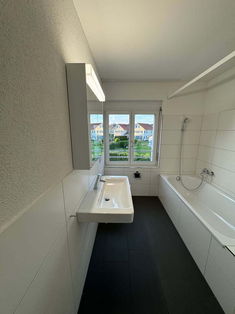 white tiles, white sink, white bathtub, shower head, mirror, window