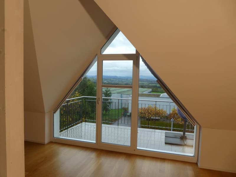 Atrium room with large windows, wooden floor, balcony with metal railings, view of the outside