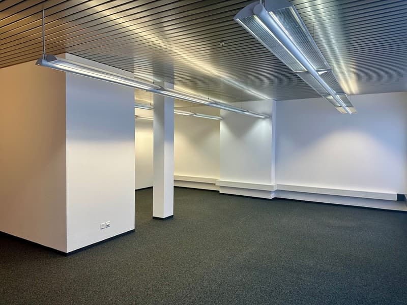 Empty room with white walls, gray floor, metal ceiling, and built-in benches