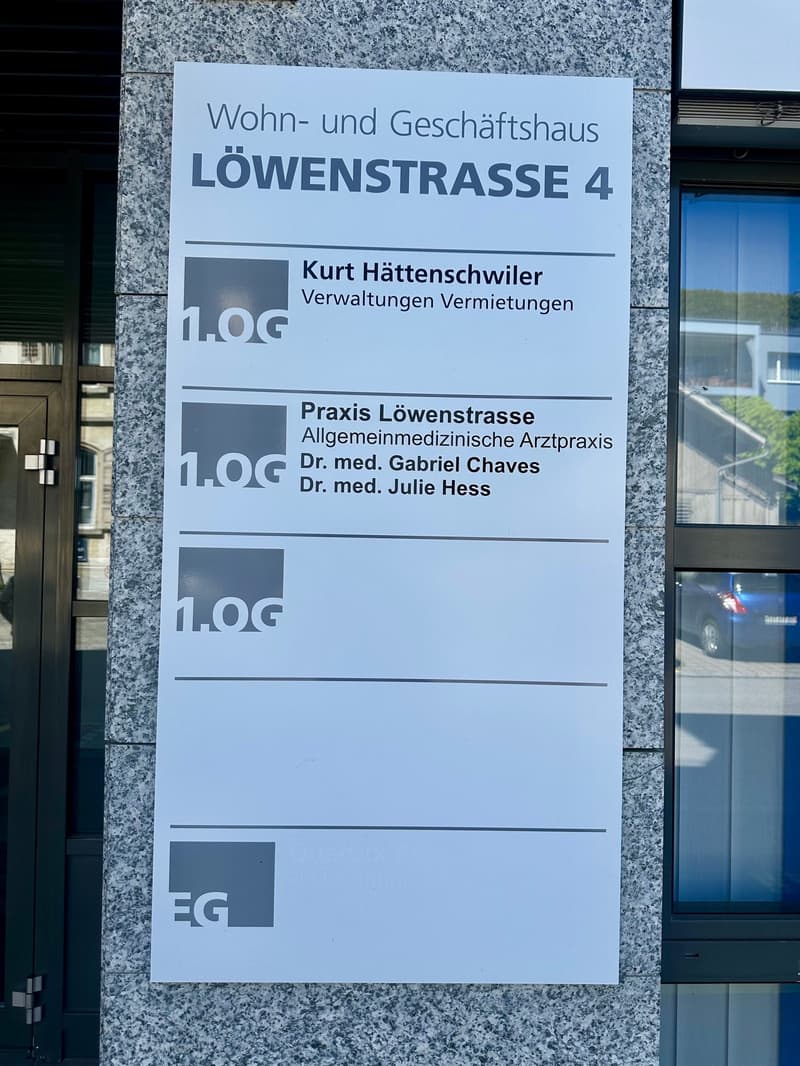 Signboard for residential and commercial building at Löwenstrasse 4, with details about the management and medical practices located there.