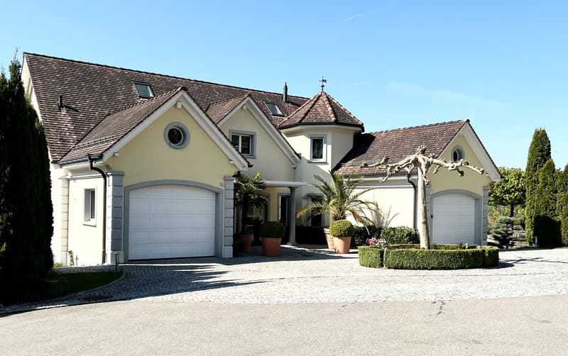 2 story house, brown roof, white walls, 2 garages, driveway, hedges, plants
