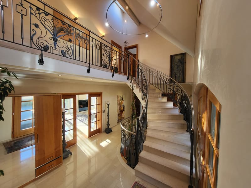 marble staircase, wooden doors, glass windows, tiled floor, decorative railings, picture frame, candle stands, chandelier