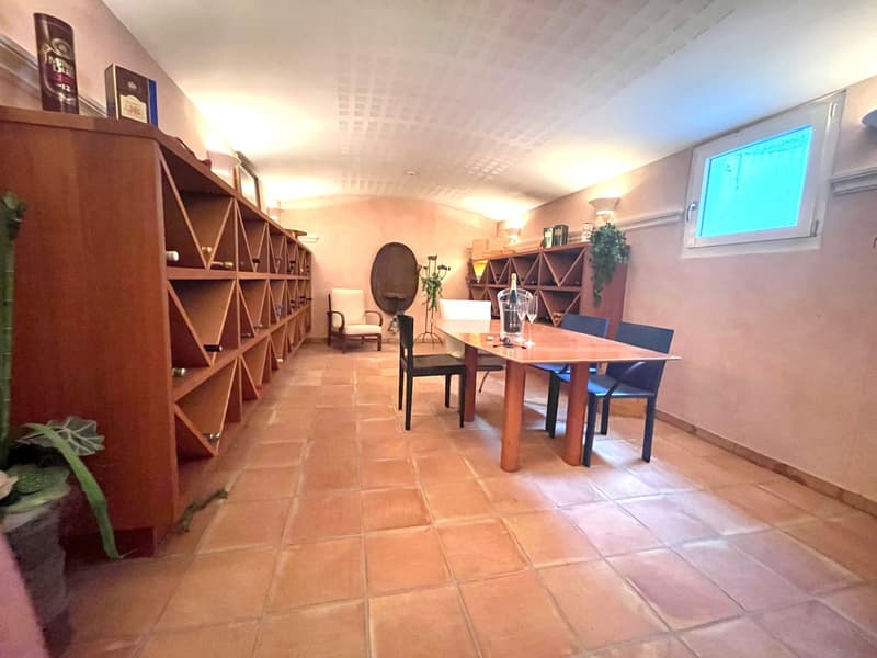 Dining room with wooden table, chairs, wine racks, and a window