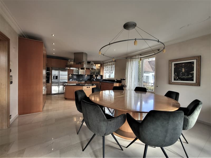 modern kitchen, dining area with large round table, wooden floor, large windows, chandelier