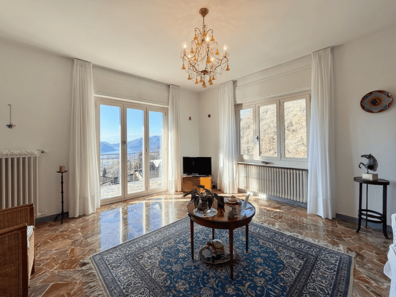 large windows, balcony, chandelier, wooden table, couch, TV, radiator, carpet
