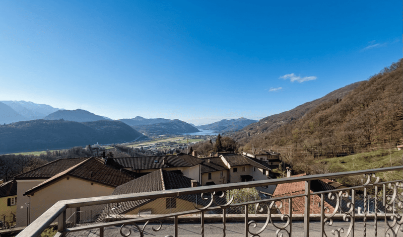 Houses with brown roofs, mountains in the background, lake, valley, clear sky