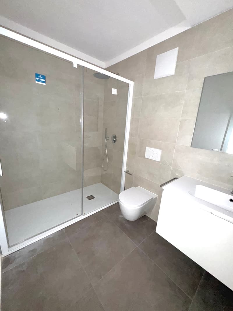 modern bathroom with shower, toilet, sink, and mirror