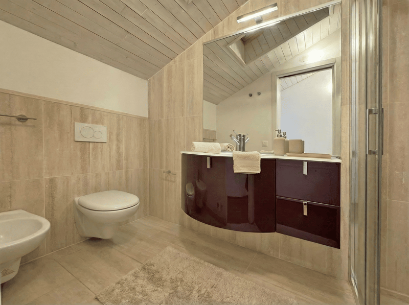 modern bathroom with white toilet, sink, and shower, wooden ceiling, tiled floor