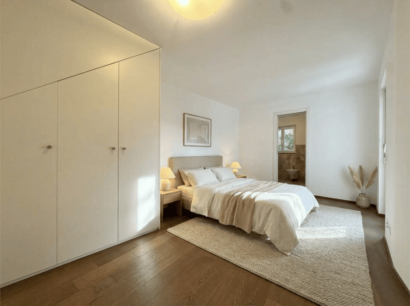 Bedroom with a bed, nightstands, lamps, rug, wardrobe, and a picture frame on the wall.