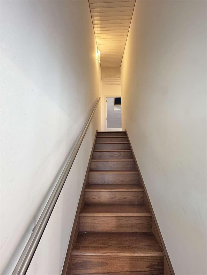 wooden steps, white walls, metal handrail, light on the wall