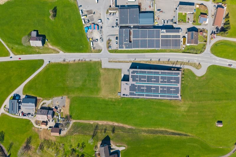 industrial building, solar panels on the roof, surrounded by green grass