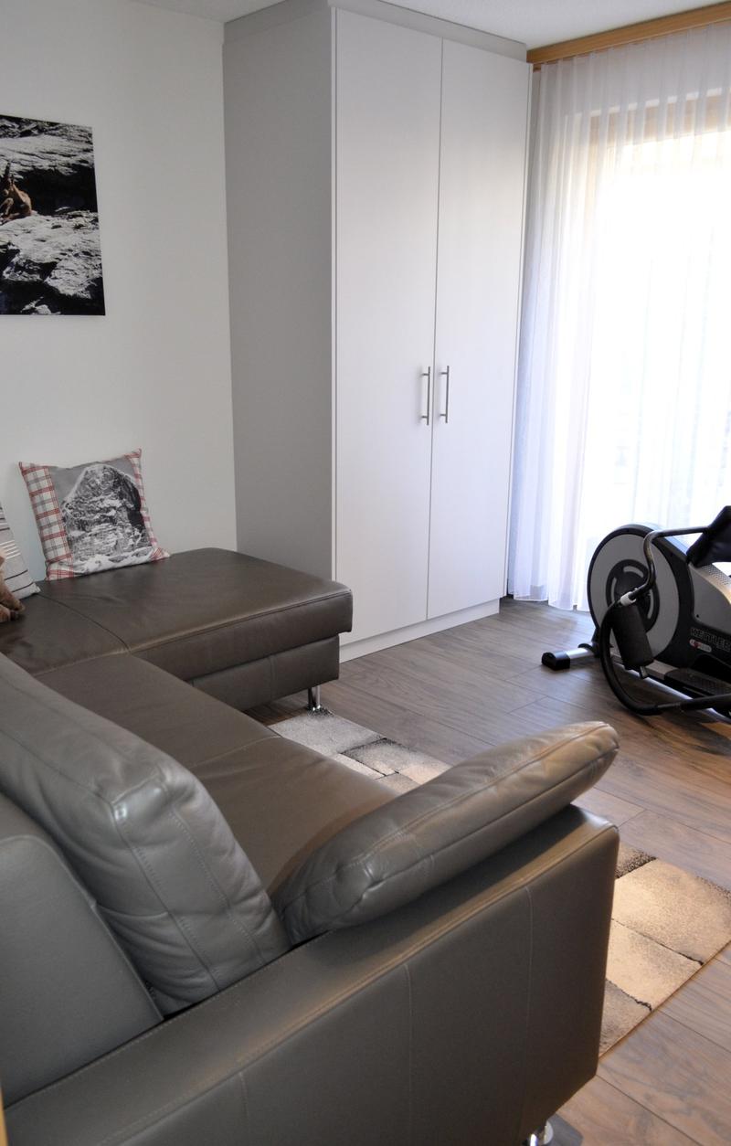 Living room with couch, cabinet, window with curtains, rug, and photo on the wall