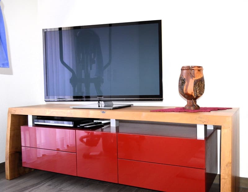 Entertainment center, flatscreen TV, red drawers, vase, wooden table