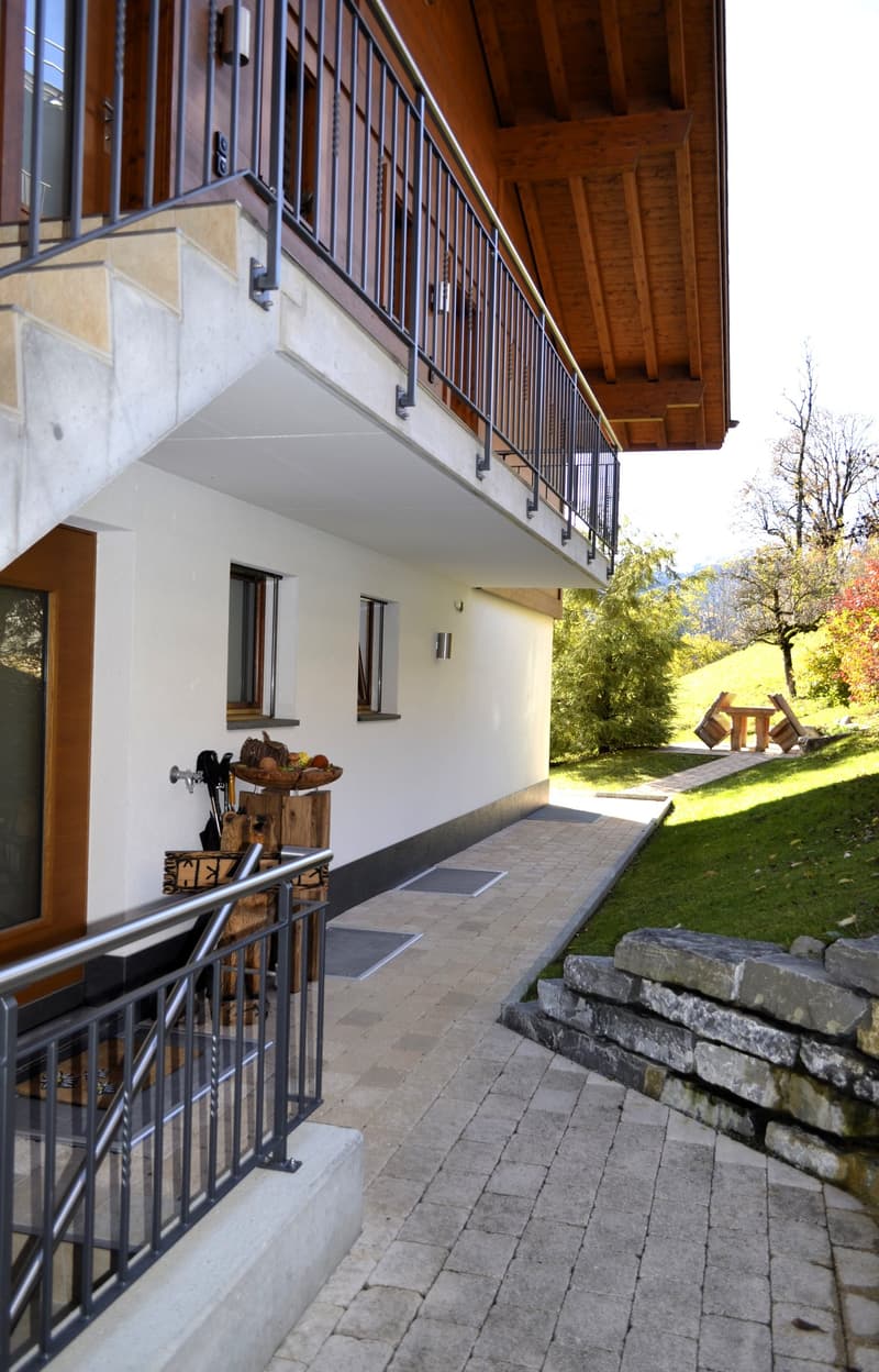 staircase, balcony, white exterior wall, brown roof, metal railing, brick footpath, grass