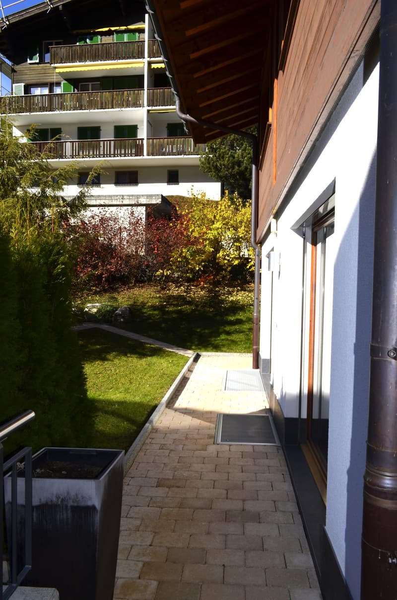 Building exterior, brick wall, brown roof, green trees, bushes, brick pathway
