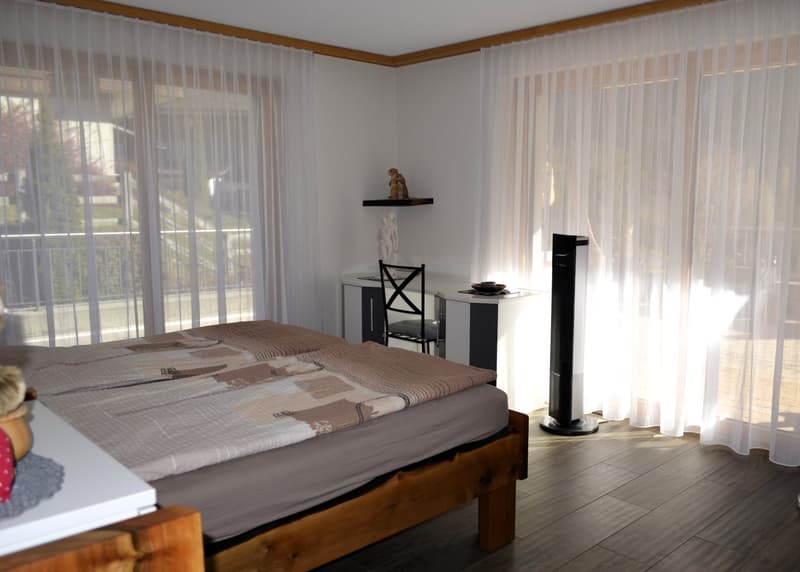 double bed, desk, chair, window with curtains, balcony