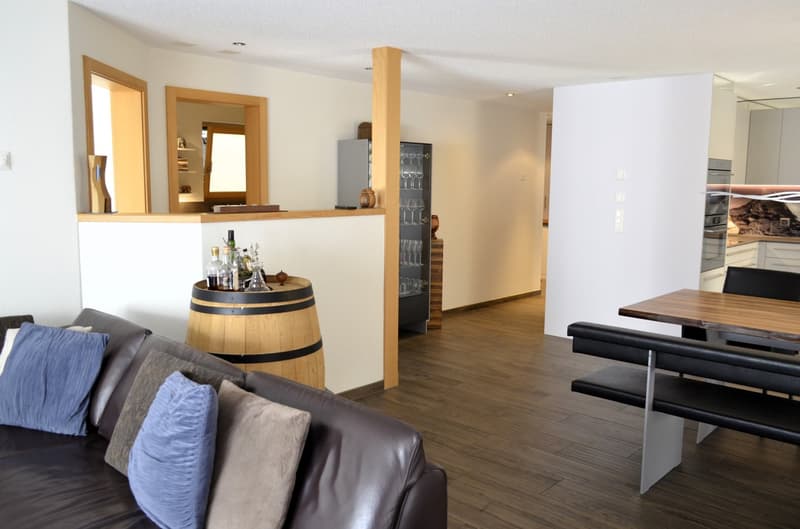 leather couch, wooden dining table, shelves with wine glasses, wooden barrel, white walls, black cushioned benches
