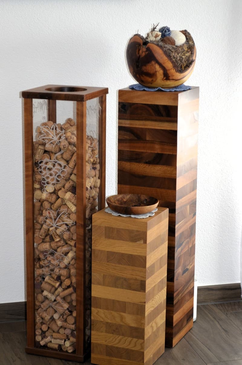 Two wooden objects, one with a glass compartment filled with wine corks, and the other having a brown bowl on top