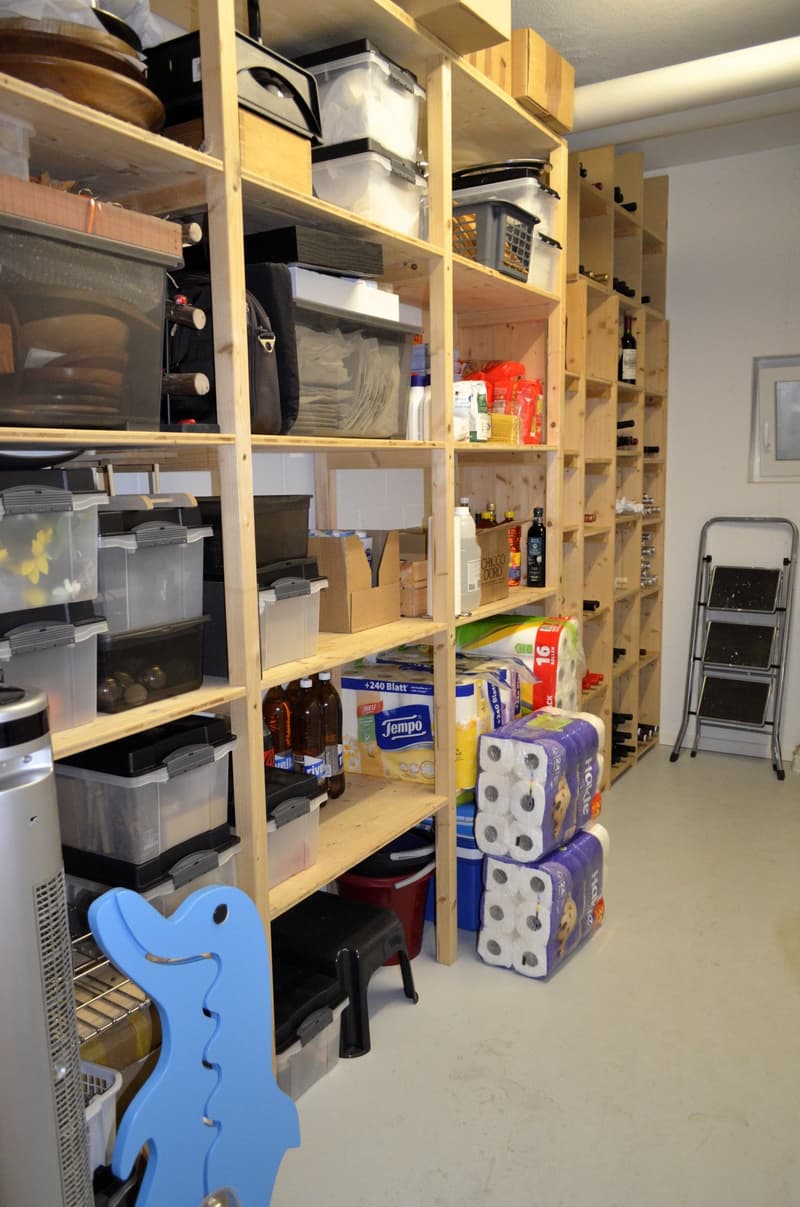 Basement with wooden shelves, containers, bottles, and cleaning supplies