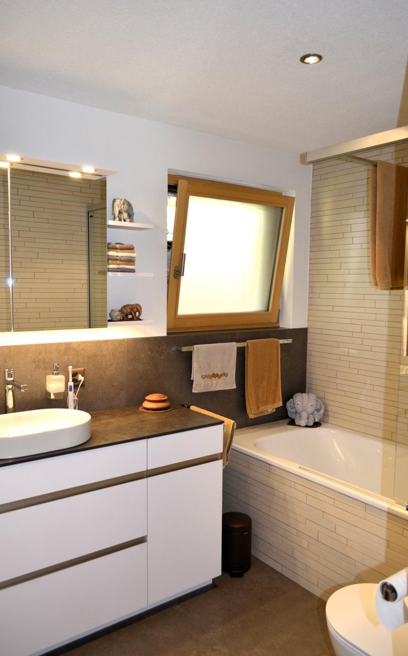 bathroom with bathtub, sink, toilet, mirror, shelves with toiletries, towels, windows
