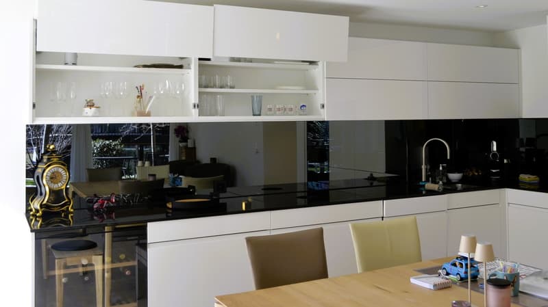 modern kitchen, white cabinets, black countertops, glass doors, wine cooler, sink, faucet, wine glasses, clock, dining table, chairs