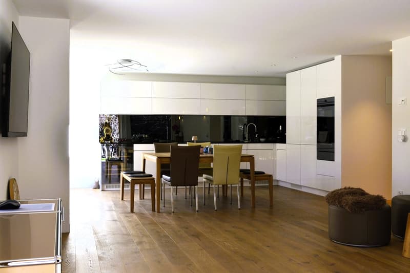 modern kitchen with dining area, wooden floor, white cabinets, black countertops, modern appliances, dining table with chairs