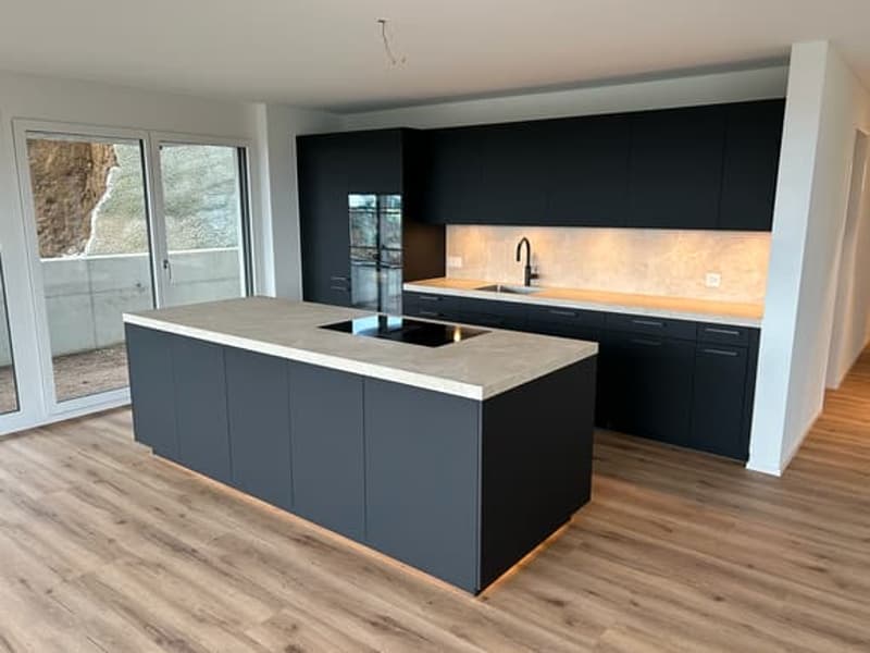 modern kitchen with black cabinets, marble countertop, island with stove, sink, faucet, sliding glass doors, wooden floor