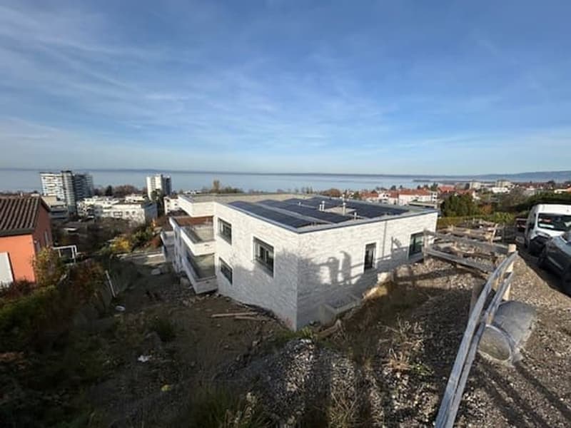 Modern house, white exterior, solar panels on the roof, elevated position, sea view