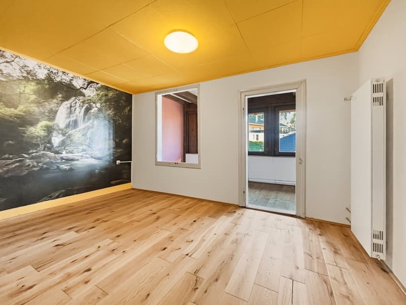 empty room with large painting, wooden floor, yellow ceiling, entrance to another room