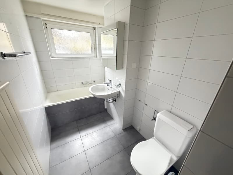 modern bathroom with white walls, tiled floor, bathtub, sink, and toilet